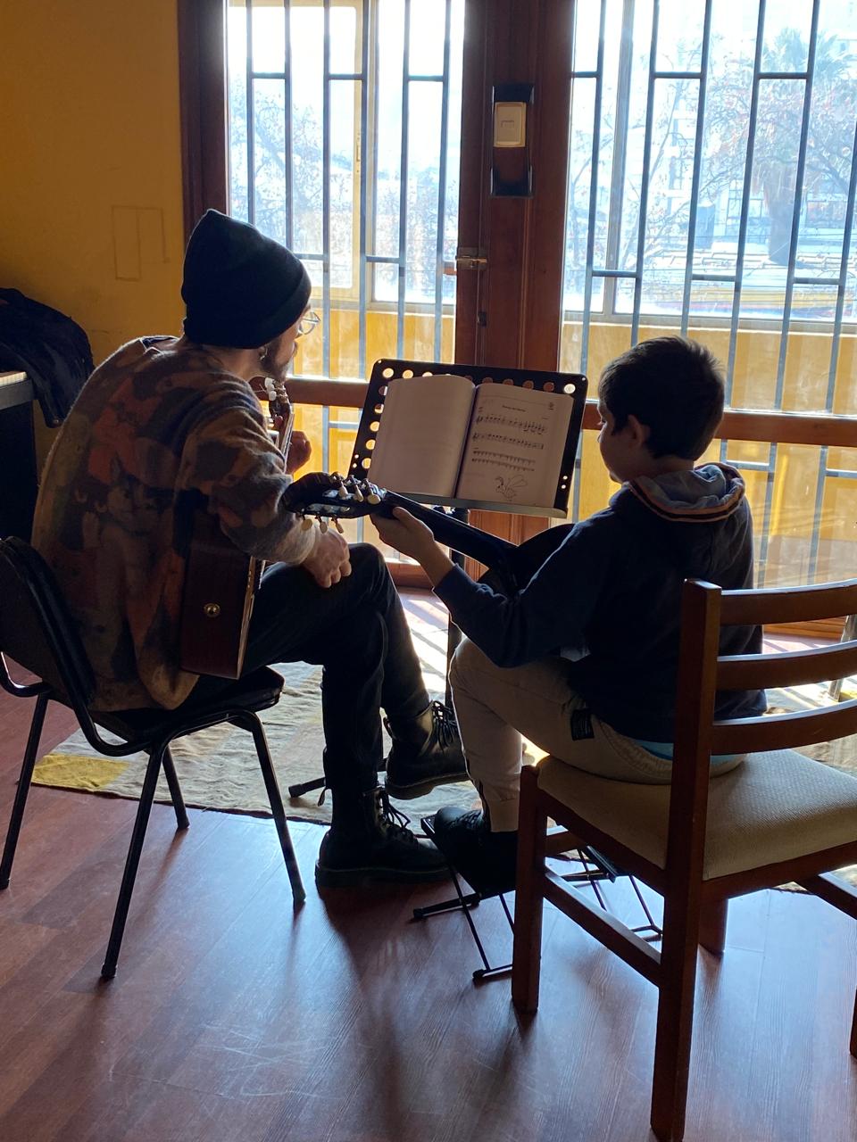 Profesor acompañando a un estudiante de guitarra